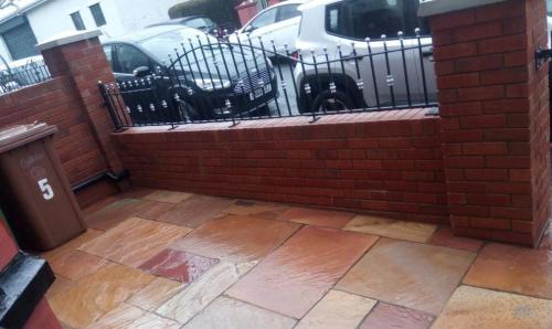 Newly build front garden red brick wall with black metal fencing between the pillars